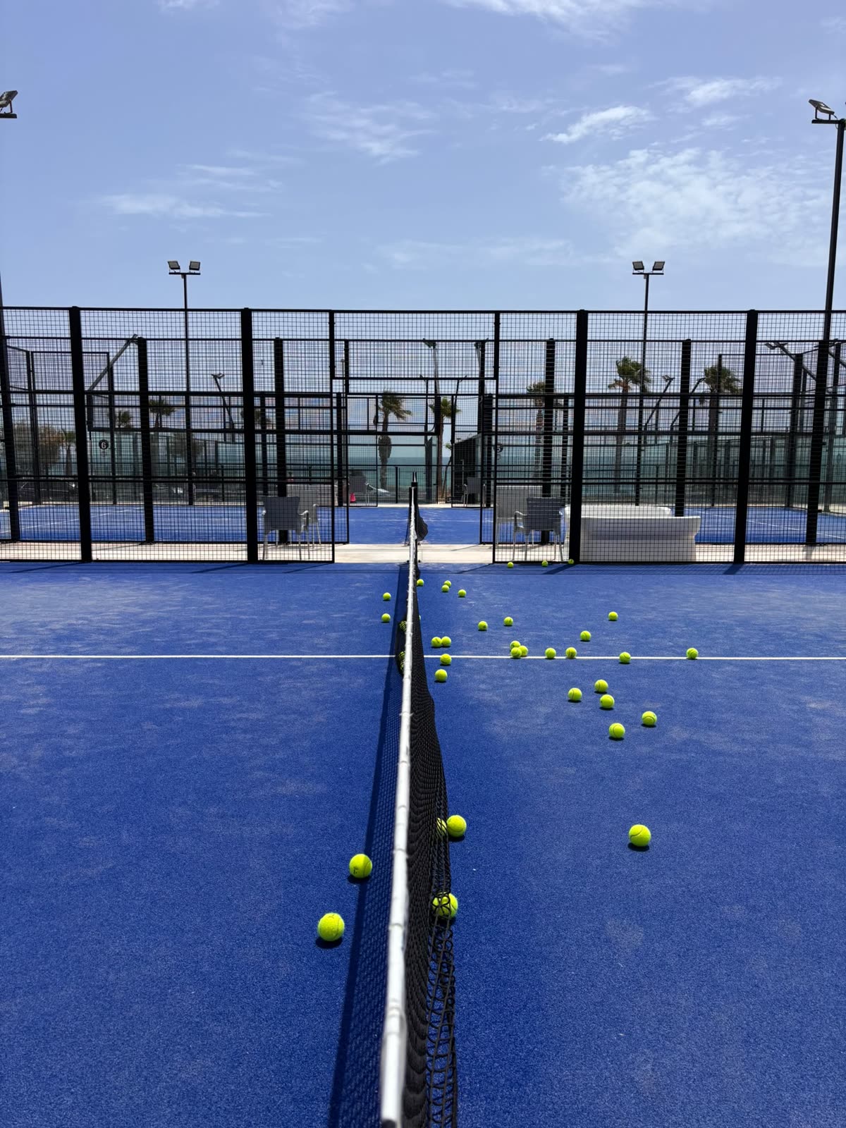 Pista de pádel azul con pelotas en la red