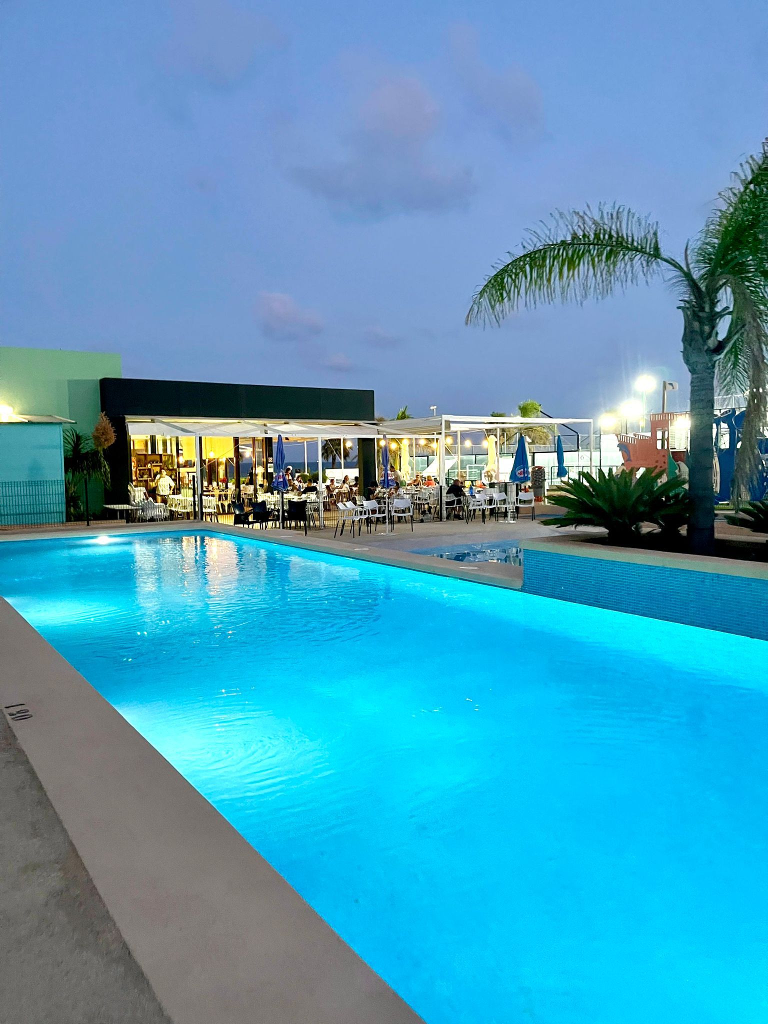 Piscina iluminada al anochecer junto a la terraza